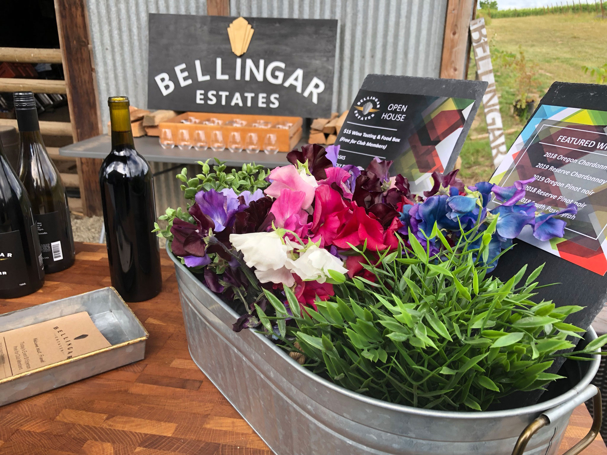 Table with a small flower bed, bottles of wine, and the Bellingar Estates sign